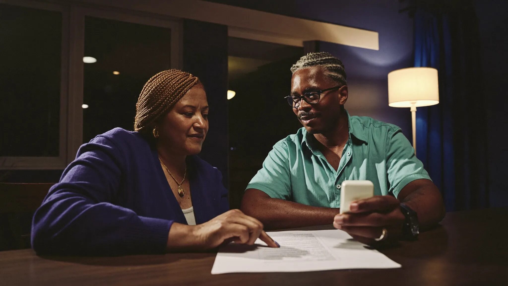 A couple at their kitchen table calmly reviewing the numbers on a car deal together